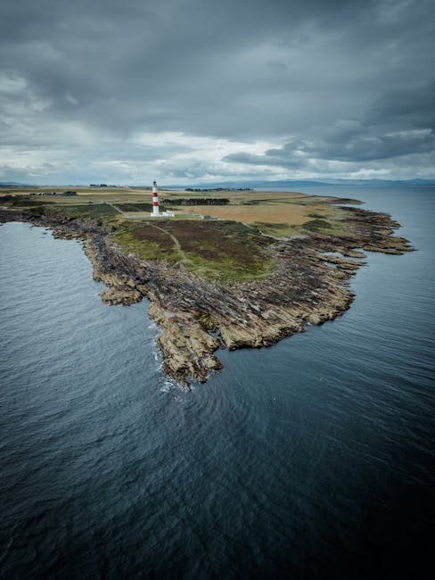 Stunning aerial view of Scotland's rugged coastline featuring a lighthouse under dramatic skies