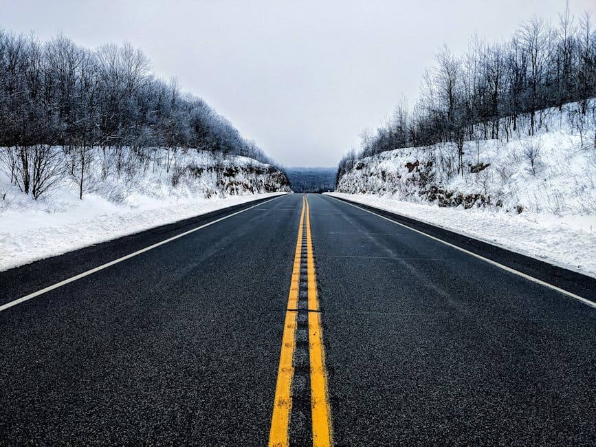 A quiet winter highway stretching through a snowy Pennsylvania forest