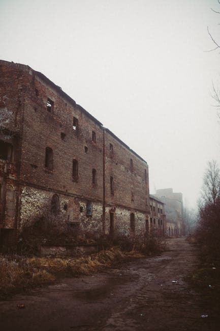 Dilapidated brick industrial building on a foggy day, reminiscent of the abandoned munitions storage buildings in the TNT area