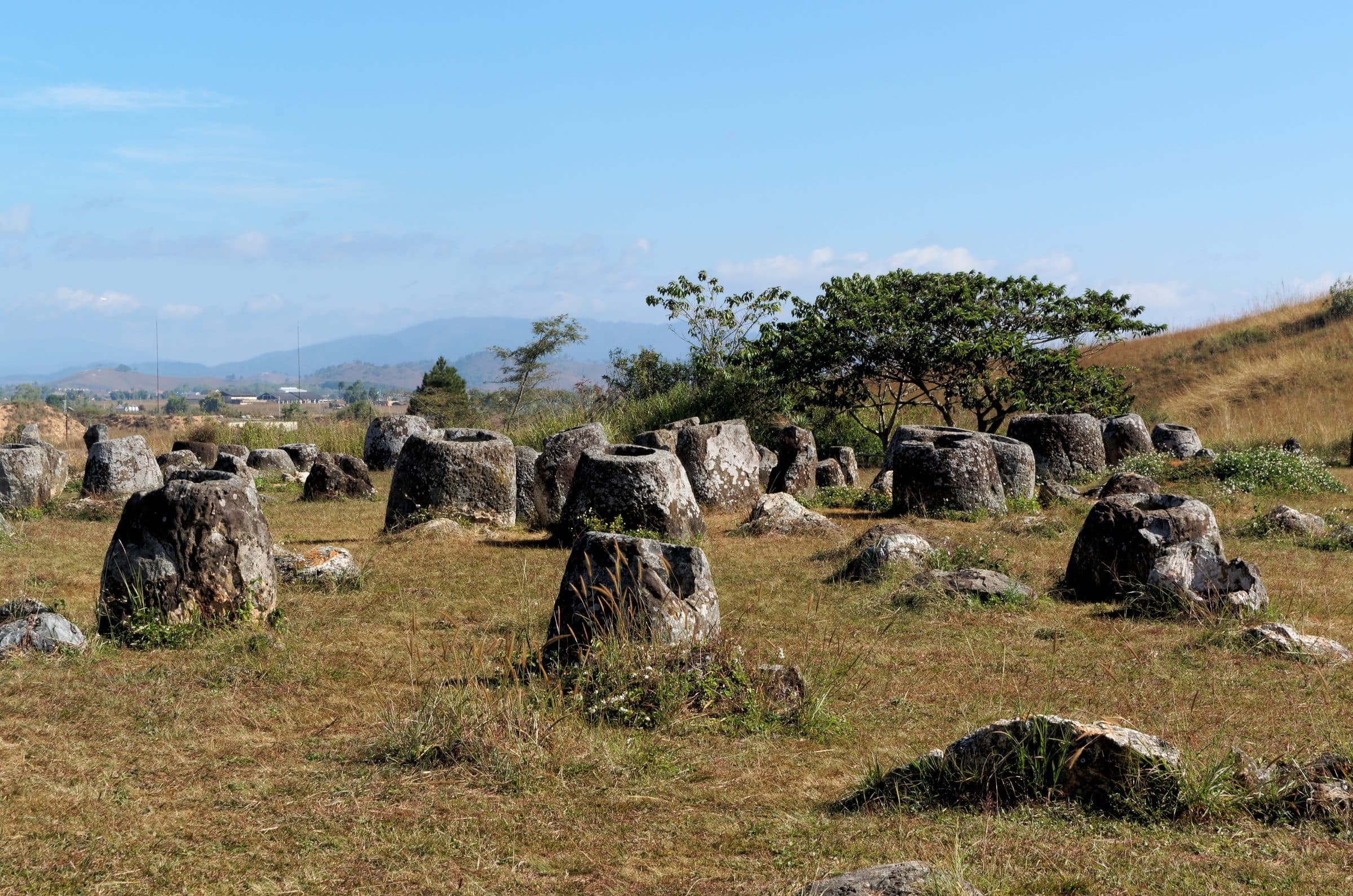 Massive ancient stone jars scattered across a grassy plateau in Xieng Khouang, Laos