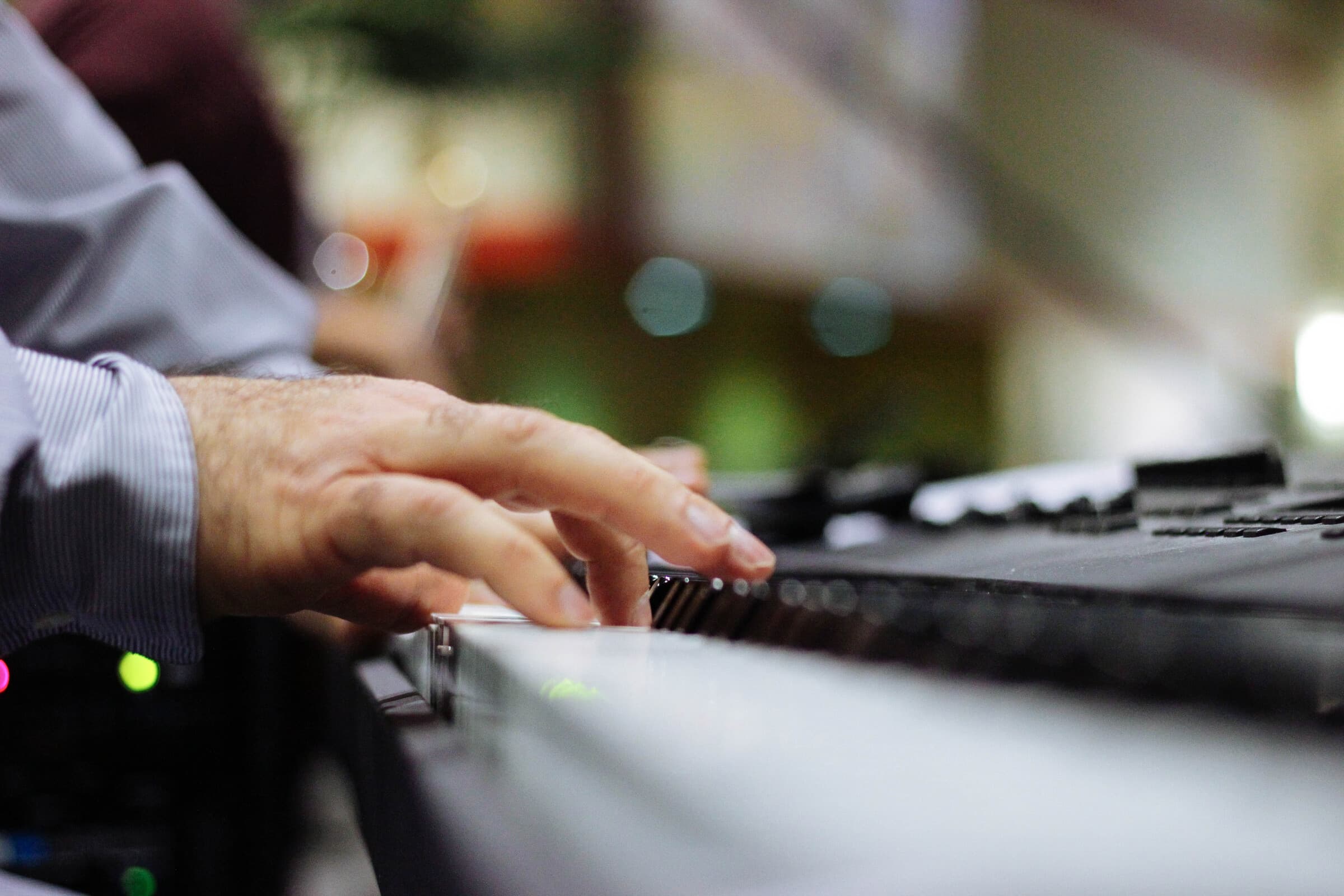 A pair of hands resting on piano keys in low, warm light