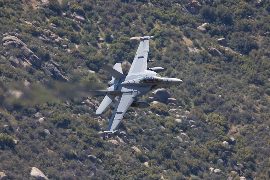 Dynamic shot of an F/A-18 Super Hornet jet flying over rugged terrain