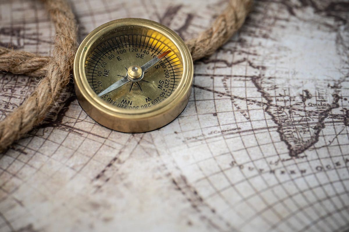 Vintage brass compass resting on an antique nautical map, representing 19th century maritime navigation